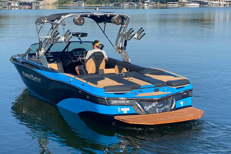 Slide: The Image of 2021 MasterCraft XT25 boat on a calm lake, featuring sleek design and modern amenities. - 5