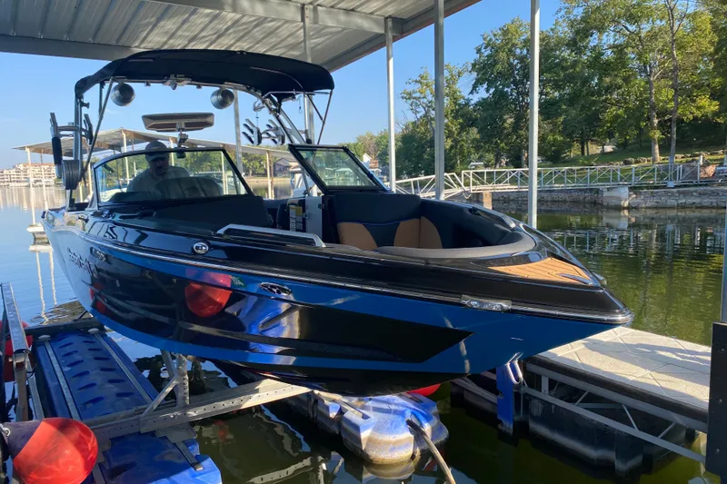 Slide: The Image of 2021 MasterCraft XT25 boat docked under a canopy on a sunny day. - 7