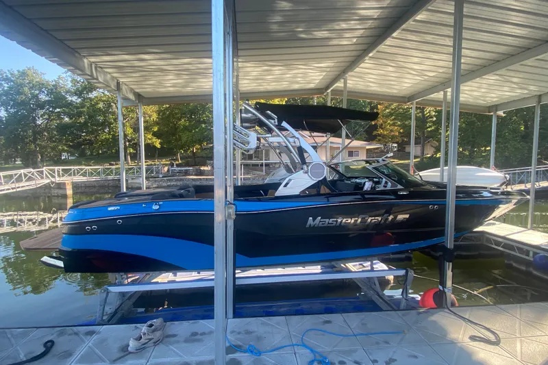 Slide: The Image of 2021 MasterCraft XT25 boat docked under a covered marina. - 8