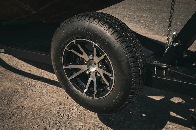 Slide: The Image of 2026 G3 Sportsman 1710 trailer wheel with Supercargo tire on gravel surface. - 19
