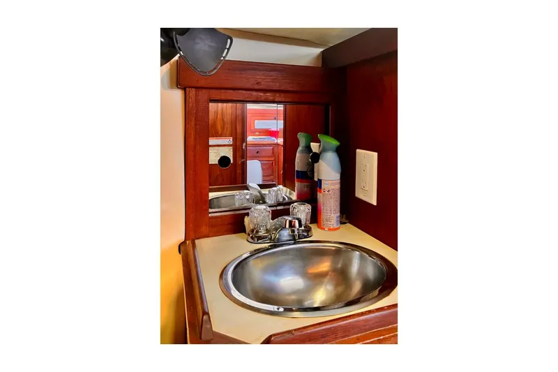 Slide: The Image of 1981 Jensen Marine/Cal Boats 39 MK III yacht bathroom sink with wooden cabinetry and cleaning supplies. - 68