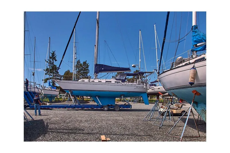 Slide: The Image of 1981 Jensen Marine/Cal Boats 39 MK III sailboat in a boatyard, surrounded by other vessels. - 80