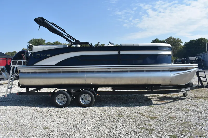 Slide: The Image of 2026 Lowe SS 230 WV pontoon boat on trailer, parked outdoors under blue sky. - 23