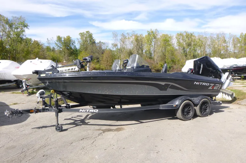 Slide: The Image of 2023 Nitro ZV21 boat on trailer, parked outdoors with trees in background. - 0