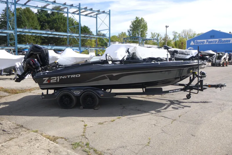 Slide: The Image of 2023 Nitro ZV21 boat on trailer at marina, surrounded by trees and equipment. - 2