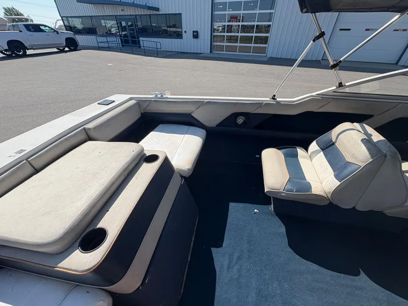 Slide: The Image of 1996 Bayliner CAPRI boat interior with cushioned seating and cup holders, parked near a building. - 3