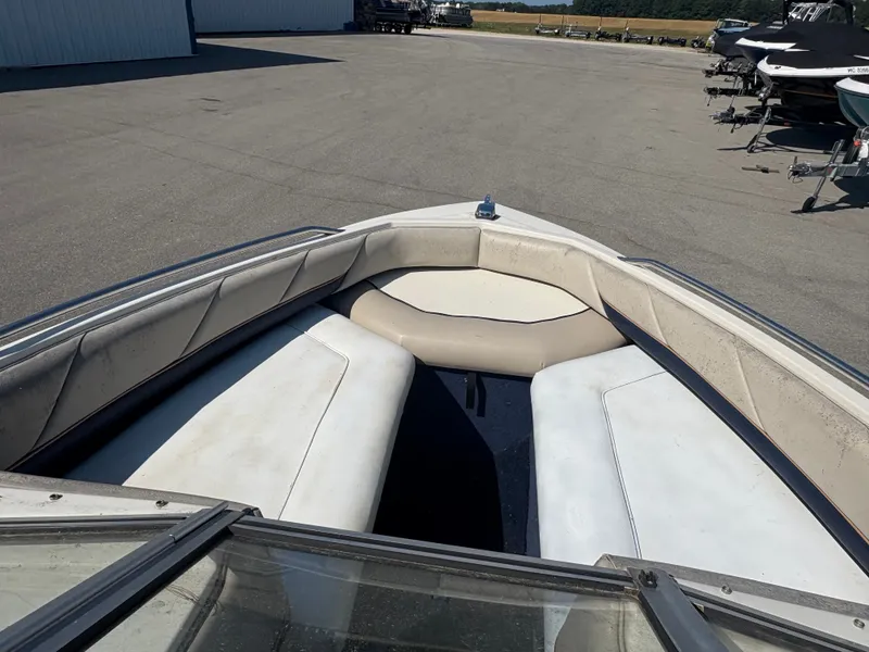 Slide: The Image of 1996 Bayliner CAPRI boat interior with white and beige seating, parked outdoors. - 5