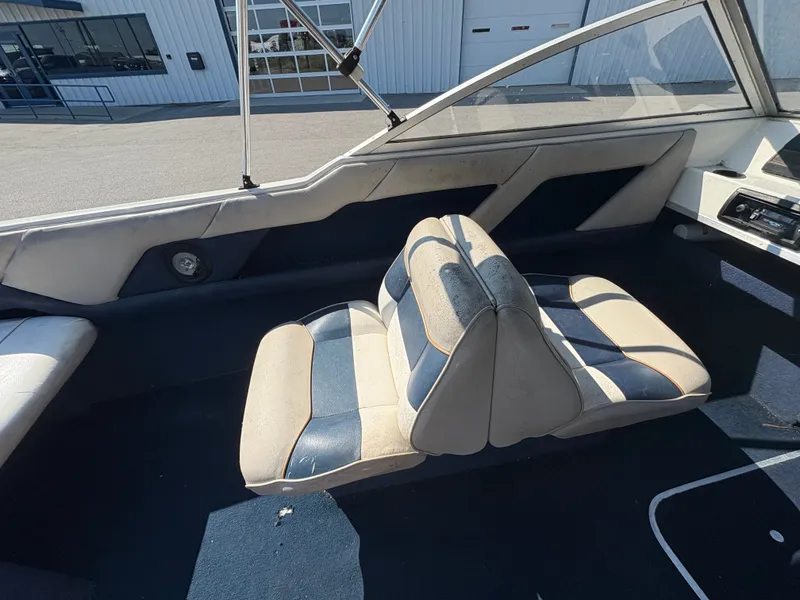 Slide: The Image of 1996 Bayliner CAPRI boat interior with blue and white seating, parked outside a building. - 6