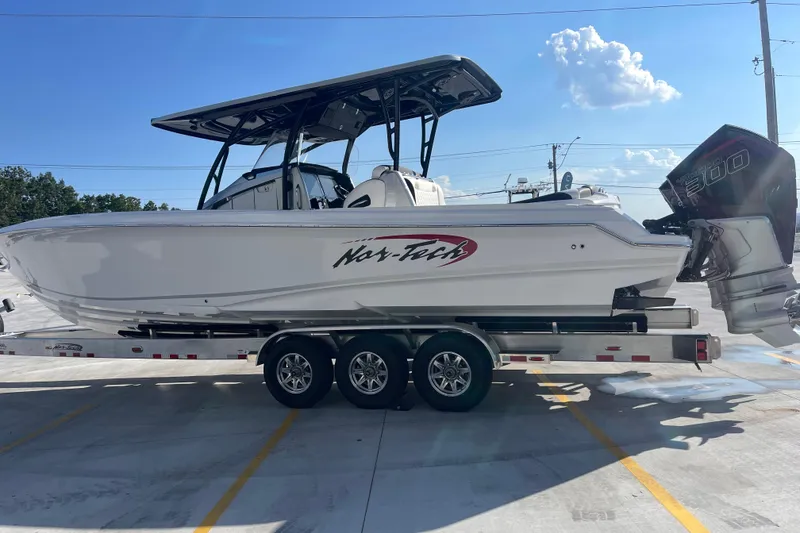 Slide: The Image of 2025 Nor-Tech 340 Sport Center Console boat on trailer, sunny day, clear sky. - 6