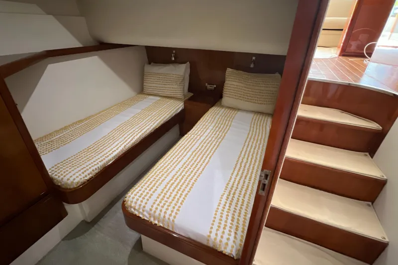 Slide: The Image of 2005 Bertram 450 yacht cabin with twin beds and wooden interior. - 11