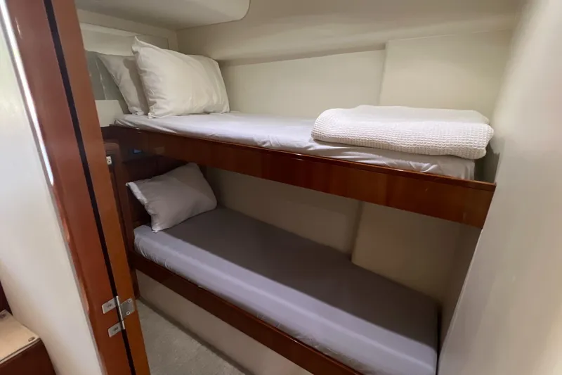 Slide: The Image of Bunk beds in 2005 Bertram 450 yacht cabin, featuring wooden frames and white bedding. - 12