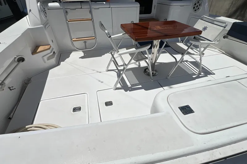 Slide: The Image of 2005 Bertram 450 yacht deck with table and chairs, featuring sleek white design. - 31