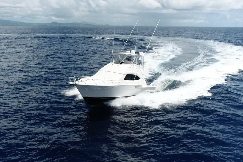 Slide: The Image of 2005 Bertram 450 yacht cruising on open ocean under cloudy skies. - 39