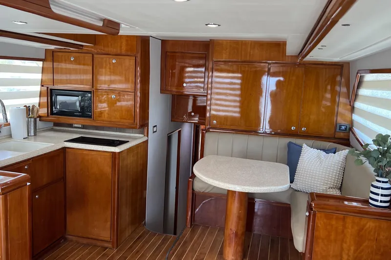 Slide: The Image of Luxurious 2005 Bertram 450 yacht interior with wood cabinetry, kitchenette, and cozy dining area. - 4