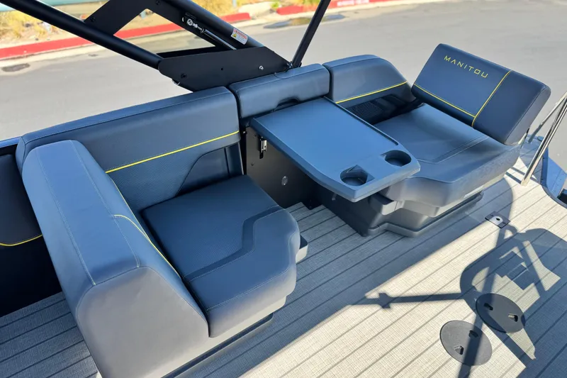 Slide: The Image of 2025 Manitou EXPLORE 24 boat interior with blue seating and foldable table. - 16