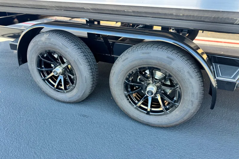 Slide: The Image of Dual black wheels of 2025 Manitou EXPLORE 24 trailer on asphalt surface. - 25