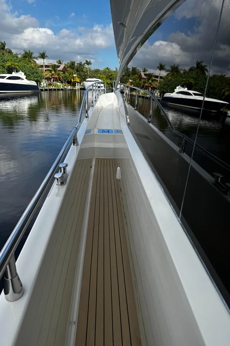 Slide: The Image of Side deck view of 2006 Marquis 65 yacht, docked in a serene marina. - 21