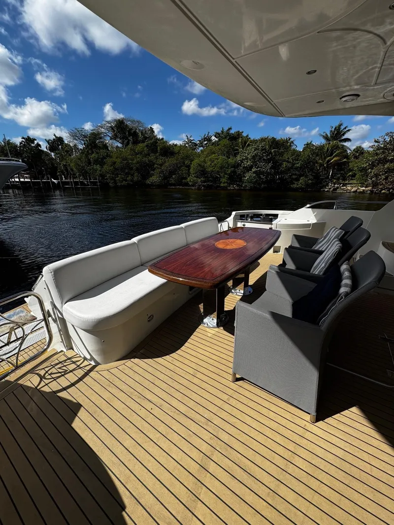 Slide: The Image of Luxury yacht deck with seating, wooden table, and scenic water view; Marquis 65, 2006 model. - 24
