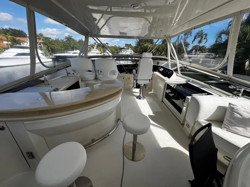 Slide: The Image of Luxurious 2006 Marquis 65 yacht interior with seating and helm, docked by palm trees. - 6