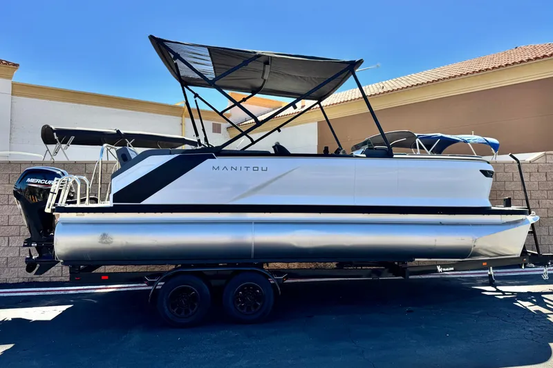 The Image of 2024 Manitou Cruise 22 pontoon boat with canopy, on trailer, side view. - 0