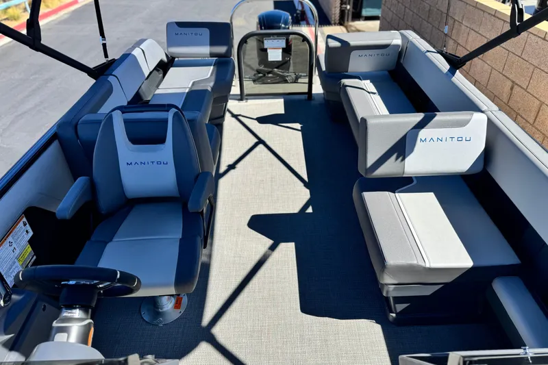 Slide: The Image of 2024 Manitou Cruise 22 pontoon boat interior with gray seating and steering wheel. - 12