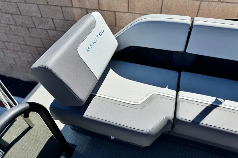 Slide: The Image of 2024 Manitou Cruise 22 boat seat with gray upholstery and logo detail. - 14