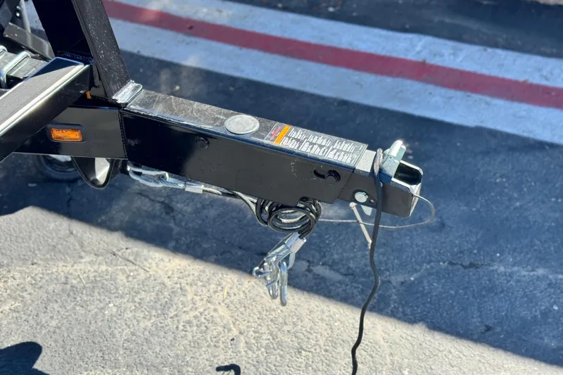 Slide: The Image of Trailer hitch of 2024 Manitou Cruise 22 boat on asphalt surface. - 24