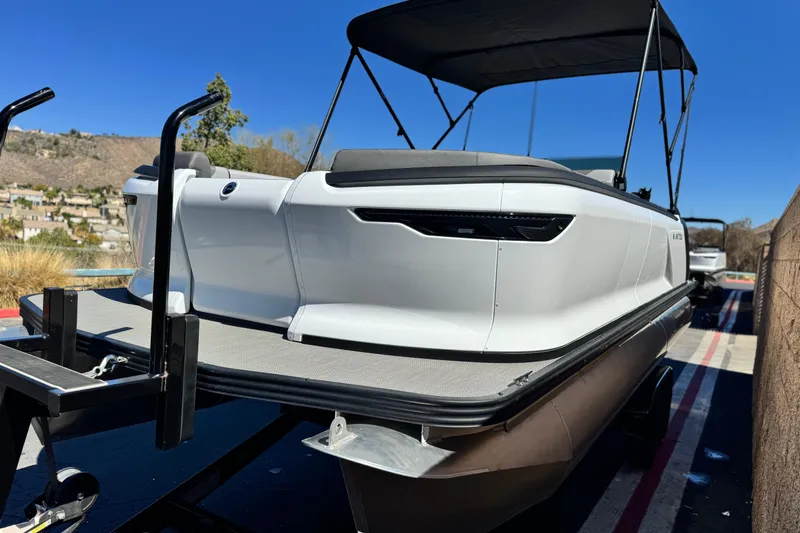 Slide: The Image of 2024 Manitou Cruise 22 pontoon boat on trailer, featuring sleek design and canopy. - 3