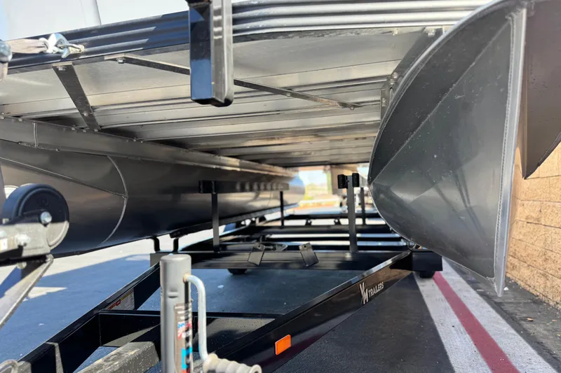 Slide: The Image of 2024 Manitou Cruise 22 pontoon boat on trailer, showcasing undercarriage and pontoons. - 4