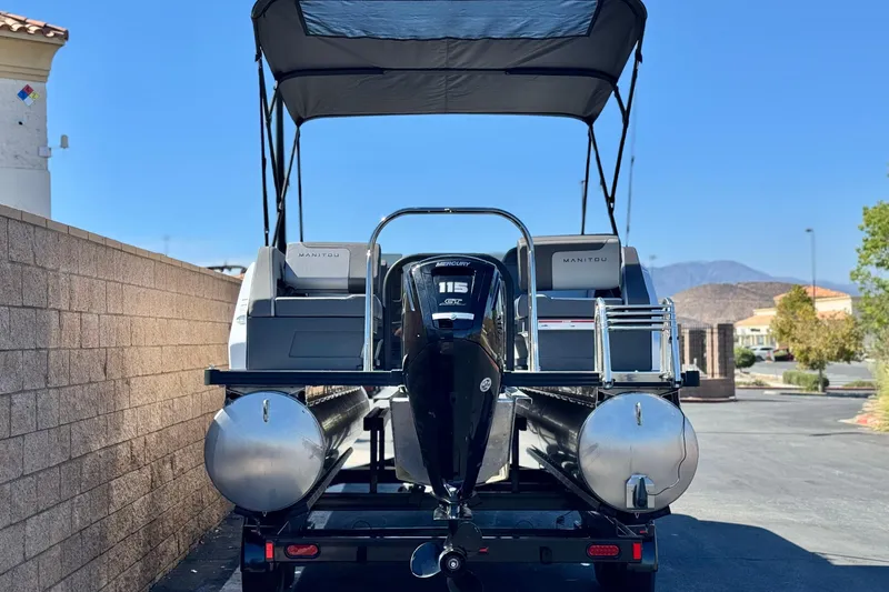 Slide: The Image of 2024 Manitou Cruise 22 pontoon boat with Mercury 115 engine, parked outdoors. - 5