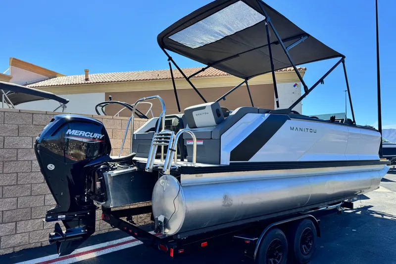 Slide: The Image of 2024 Manitou Cruise 22 pontoon boat with Mercury engine, parked on trailer. - 6
