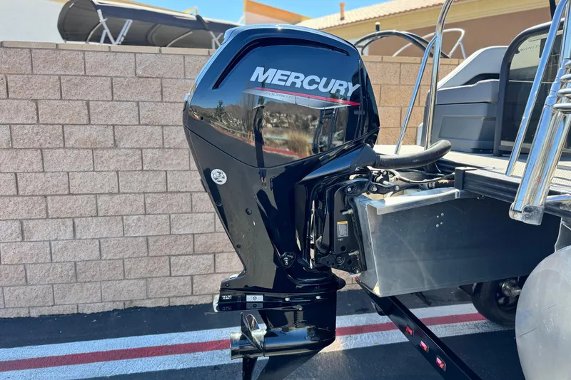 Slide: The Image of 2024 Manitou Cruise 22 with Mercury outboard motor, parked near a brick wall. - 7