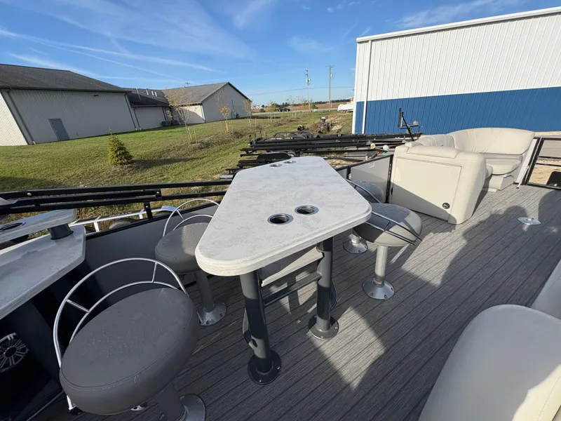 Slide: The Image of 2018 Starcraft CX 23 RE pontoon boat interior with seating and table, outdoor setting. - 10