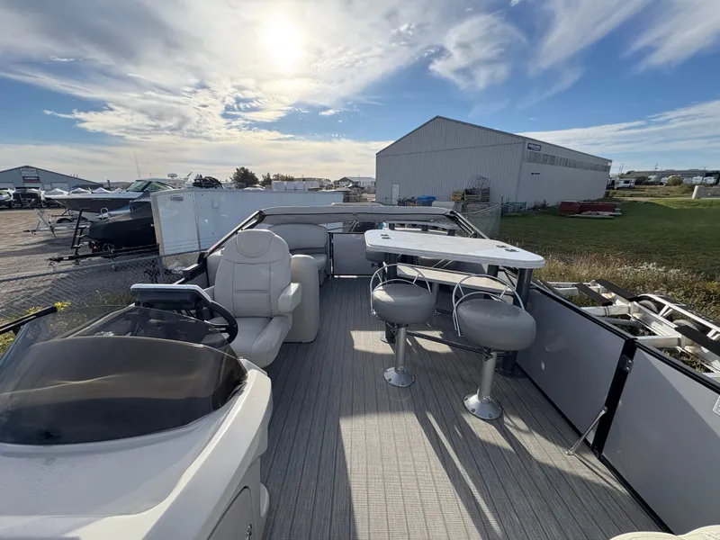 Slide: The Image of 2018 Starcraft CX 23 RE pontoon boat with seating and table, under a sunny sky. - 12