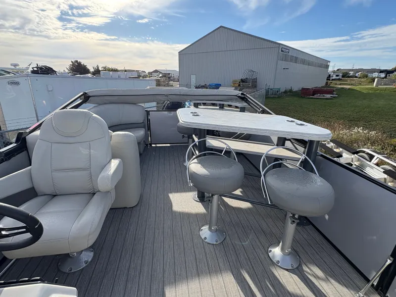 Slide: The Image of 2018 Starcraft CX 23 RE boat interior with seating and table, parked outdoors. - 6