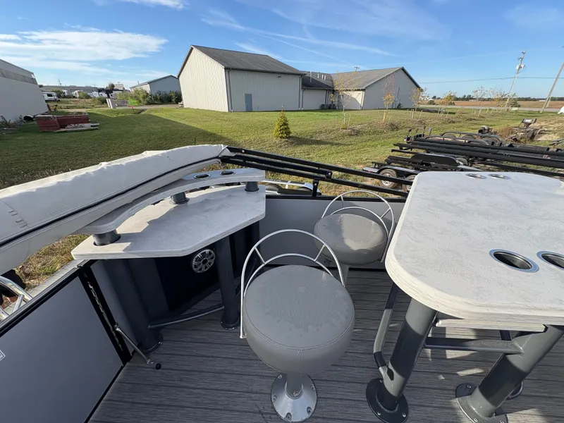 Slide: The Image of 2018 Starcraft CX 23 RE pontoon boat interior with seating and table, outdoor setting. - 9