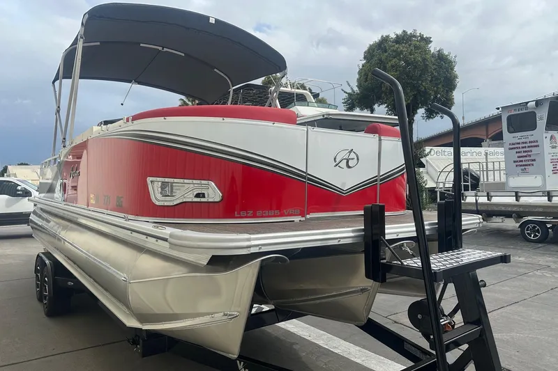 Slide: The Image of 2024 Avalon LSZ 2385 VRB pontoon boat with red and white design on a trailer. - 4