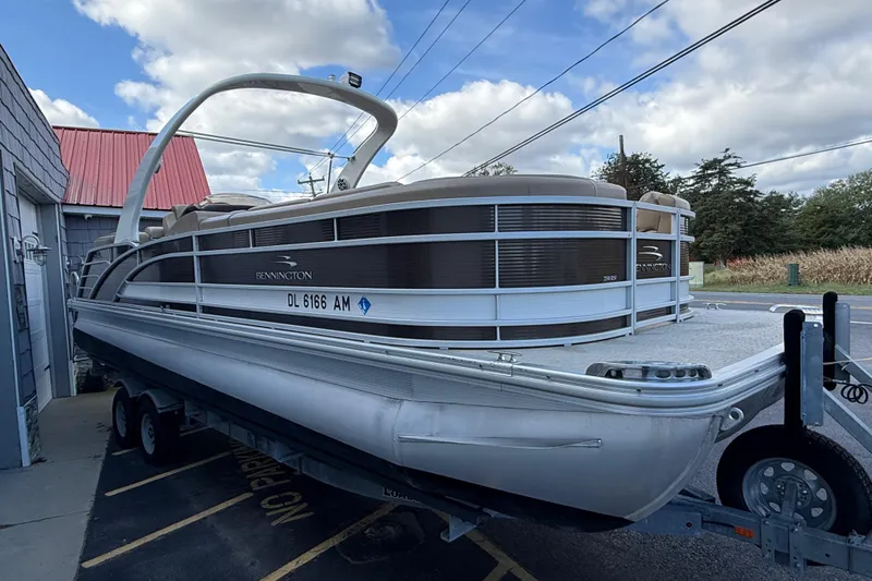 Slide: The Image of 2016 Bennington 2550 RSF Arch Tri Toon pontoon boat on trailer, parked outdoors. - 11