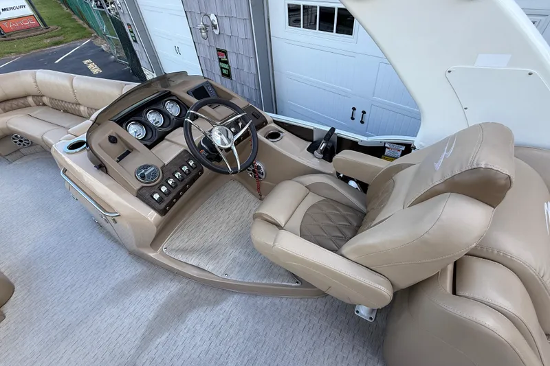 Slide: The Image of 2016 Bennington 2550 RSF Arch Tri Toon boat interior with beige captain's chair and dashboard. - 17