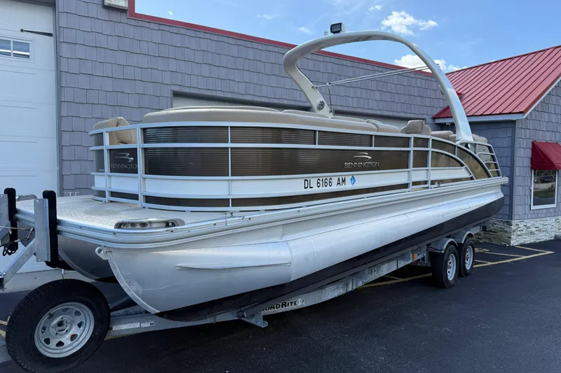 Slide: The Image of 2016 Bennington 2550 RSF Arch Tri Toon pontoon boat on trailer, parked outside building. - 2