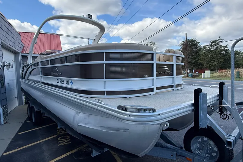 Slide: The Image of 2016 Bennington 2550 RSF Arch Tri Toon pontoon boat on trailer, parked outdoors. - 9