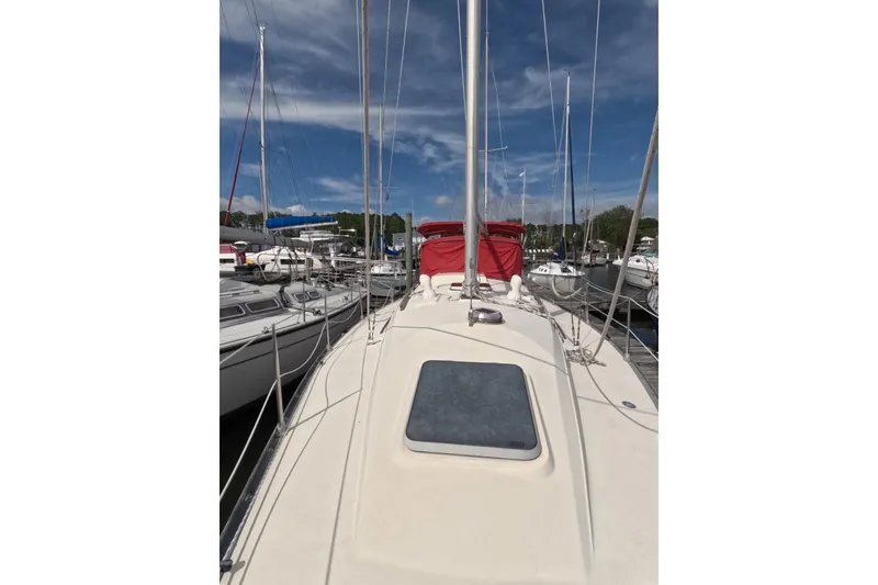 Slide: The Image of 1985 Mirage 35 sailboat docked, featuring a sleek deck and vibrant red cover. - 17