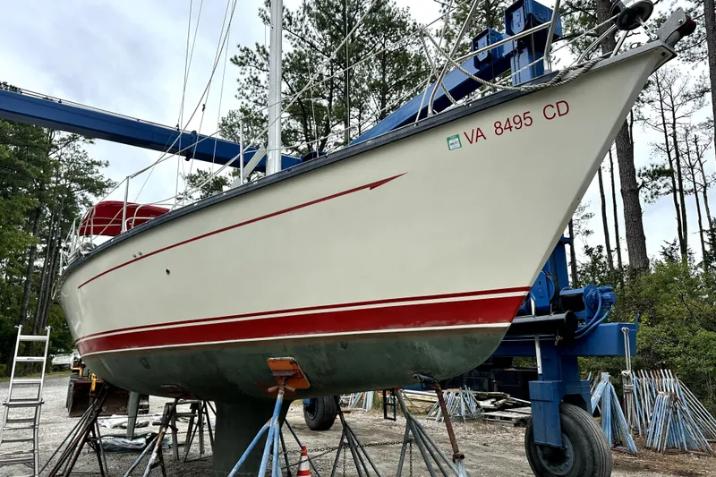 Slide: The Image of 1984 Mirage 35 sailboat on a lift, displaying red stripe and registration number. - 22