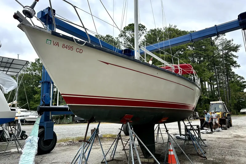 Slide: The Image of 1984 Mirage 35 sailboat on stands in a boatyard, with workers nearby. - 23