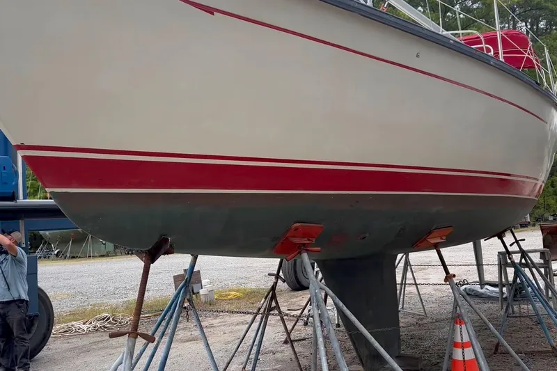 Slide: The Image of 1984 Mirage 35 sailboat on stands, red stripe, outdoor setting. - 24