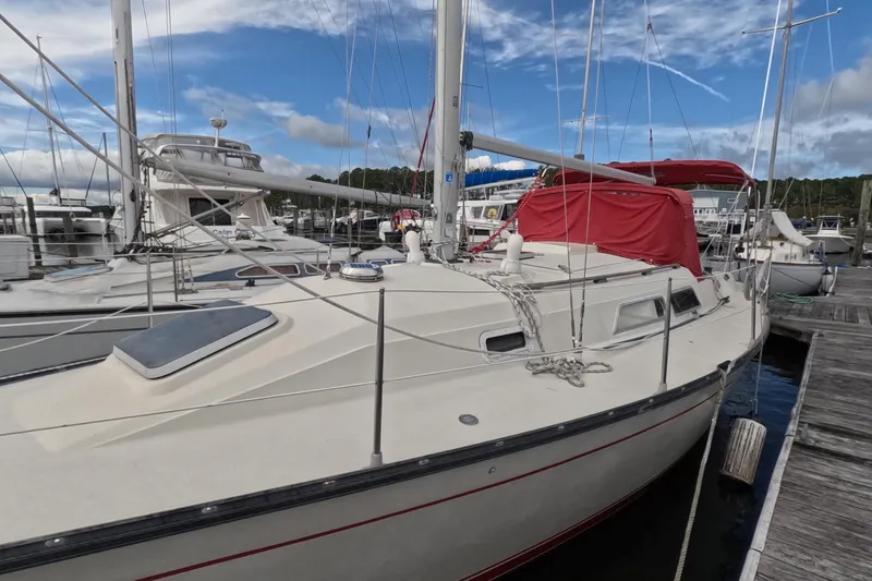 Slide: The Image of 1985 Mirage 35 sailboat docked at marina with red cover and clear sky. - 3