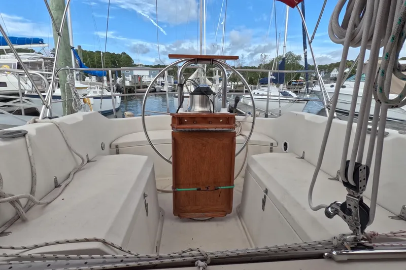 Slide: The Image of Cockpit of a 1985 Mirage 35 sailboat docked at a marina, featuring a wooden helm. - 7