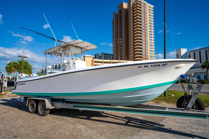 Slide: The Image of 1997 Contender 27 boat on trailer, urban background, clear sky. - 1