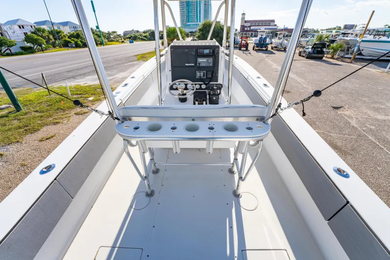 Slide: The Image of 1997 Contender 27 boat interior with steering console and rod holders, docked near a road. - 12
