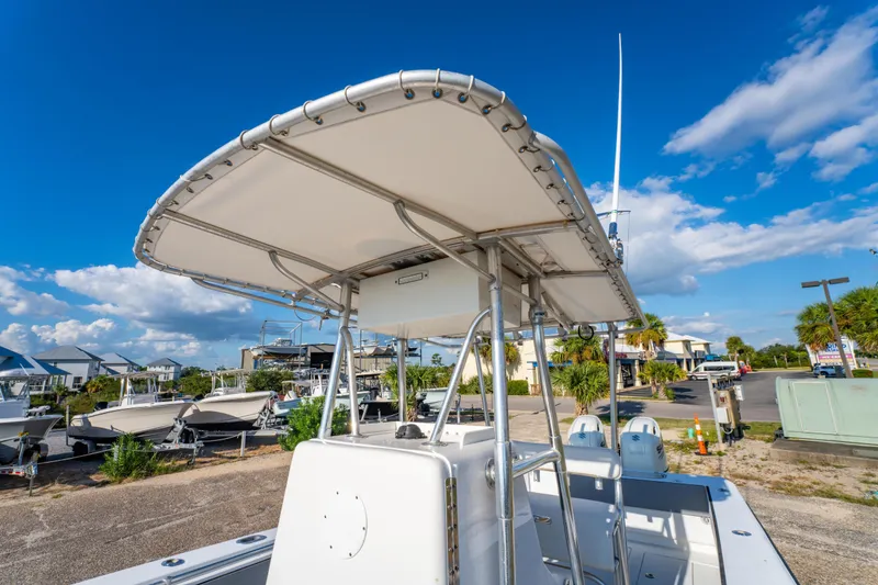 Slide: The Image of 1997 Contender 27 boat with T-top, parked outdoors under a clear blue sky. - 19